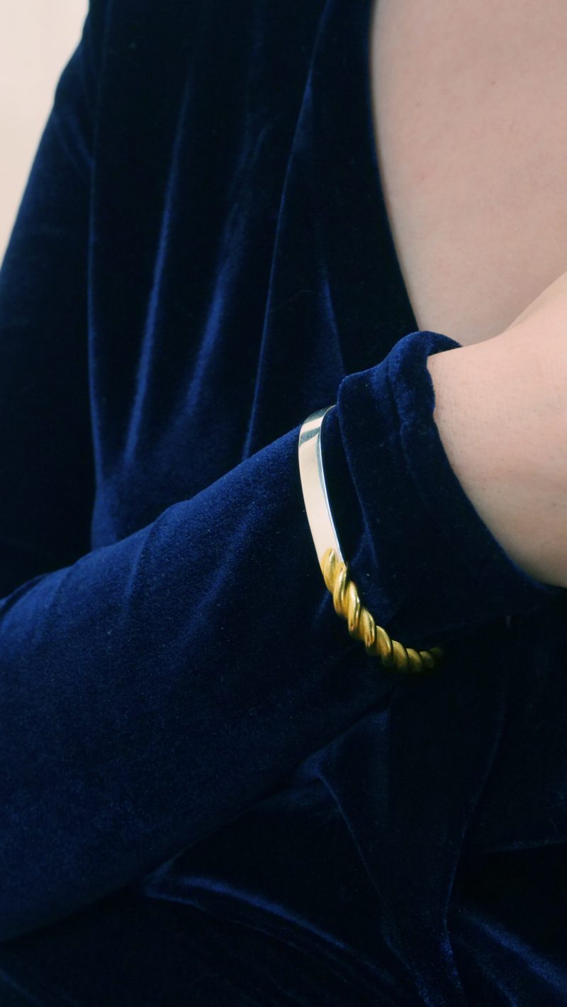 le bracelet hachi de l'édition limitée kami doré bicolore en argent 925 et argent doré vermeil, porté sur un poigne droit sur une robe bleue en velours
